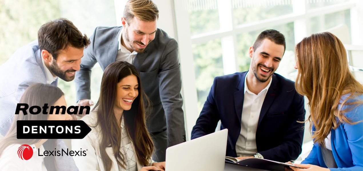 Coworkers gathered around table with half looking at a laptop screen